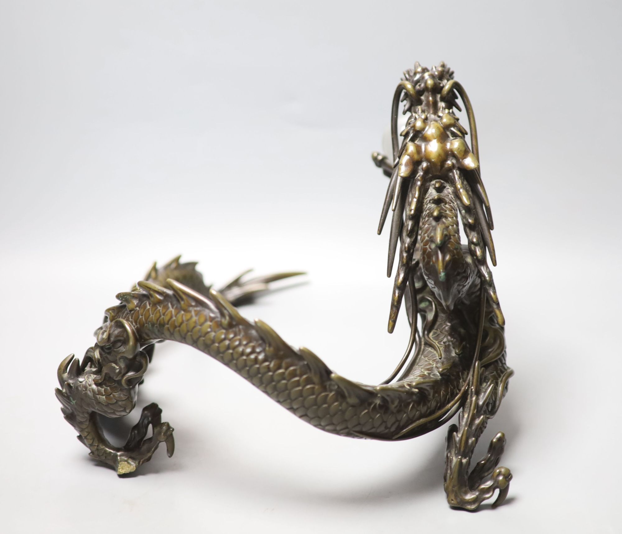 A large Japanese bronze model of a dragon clasping a glass jewel, 29.5cm across